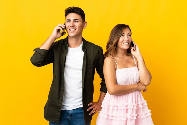 Sarı Arka Planda Izole Edilmiş Genç Beyaz Çift Cep Telefonuyla — Stok fotoğraf