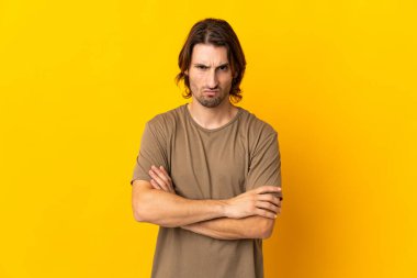 Sarı arka planda izole edilmiş yakışıklı genç adam üzgün hissediyor.