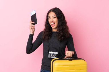 İzole edilmiş pembe geçmişi olan melez bir kadın, valiz ve pasaportla tatilde.