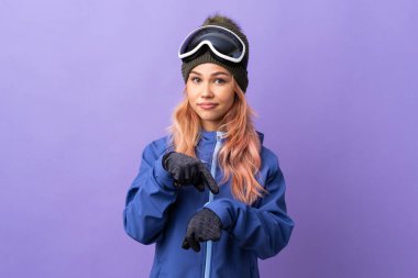 Kar kayağı gözlüklü genç kız izole edilmiş mor arka planda geç kalma jesti yapıyor.