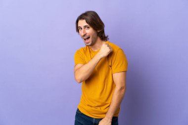 Mor arka planda izole genç yakışıklı bir adam zaferi kutluyor.