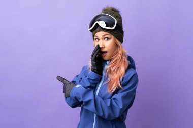 Kayakçı kız, kayak gözlükleriyle mor arka planda bir ürün sunup bir şeyler fısıldıyor.