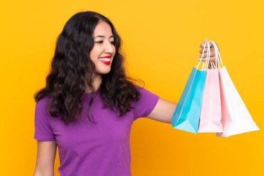 Alışveriş çantalı İspanyol kadın izole edilmiş arka planda mutlu bir ifadeyle.