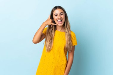 Genç İspanyol kadın izole edilmiş mavi arka planda telefon jesti yapıyor. Bana geri dönüş işareti ver.