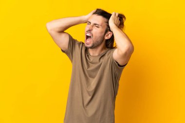 Sarı arka planda izole genç yakışıklı adam stresli