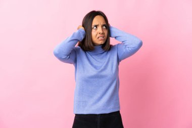 Pembe arka planda izole edilmiş genç Latin kadın hayal kırıklığına uğramış ve kulaklarını kapatmış.