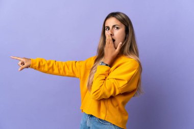 Soyutlanmış mor arka planda genç İspanyol bir kadın. Sürpriz bir ifadeyle işaret ederken
