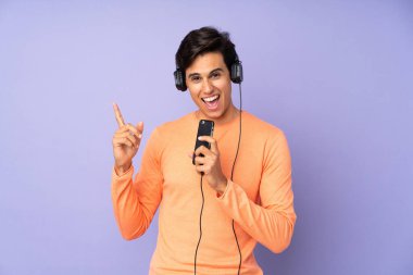İzole edilmiş mor arka plan müzik dinleyen ve şarkı söyleyen bir adam.