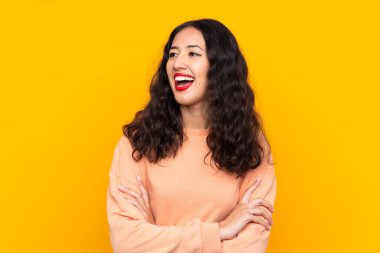 İspanyol Çinli kadın izole edilmiş sarı arka planda mutlu ve gülümsüyor.