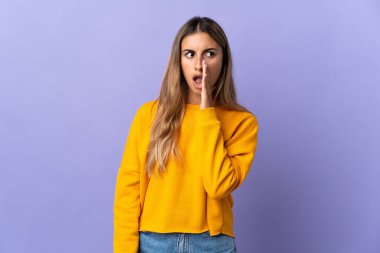 Soyutlanmış mor arka planı olan genç İspanyol kadın yan tarafa bakarken sürpriz bir jest yapıyor.