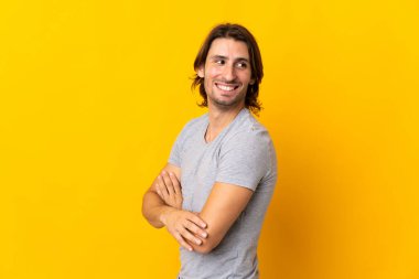 Sarı arka planda izole edilmiş, kolları bağlı ve mutlu genç bir adam.