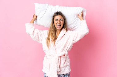 Pijamalı, pembe arka planda ve elinde yastıkla gezen genç İspanyol kadın bunalımda.