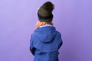 Snowboard gözlüklü kayakçı kız arka planda izole edilmiş mor arka planda.