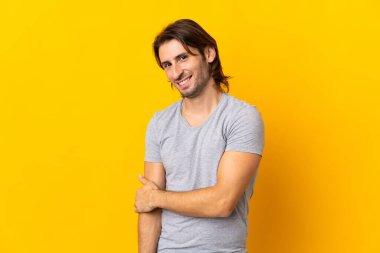 Sarı arka planda yalnız yaşayan yakışıklı bir adam gülüyor.