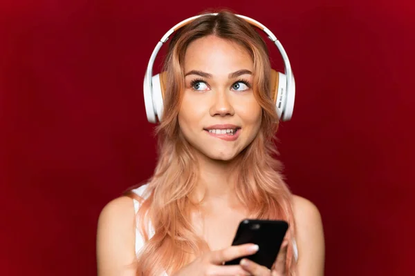Adolescente Aux Cheveux Roses Sur Fond Rouge Isolé Écoutant Musique — Photo