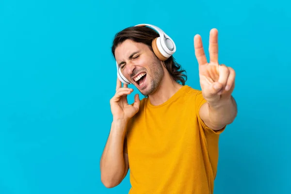 Jonge Knappe Man Geïsoleerd Blauwe Achtergrond Luisteren Muziek Zingen — Stockfoto