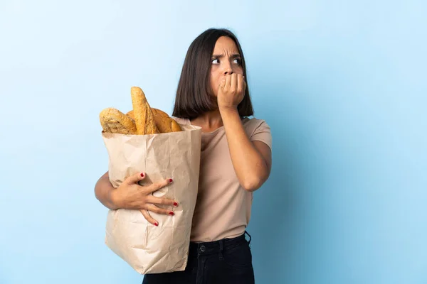 Молодая Латиноамериканка Покупает Хлеб Изолированный Синем Фоне Нервничает Боится Класть — стоковое фото
