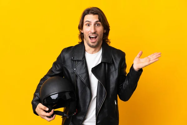 ショックを受けた顔の表情で黄色の背景に隔離されたオートバイのヘルメットを持つ男 — ストック写真