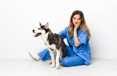 Sibiryalı Husky köpeği olan veteriner doktor yerde mutsuz ve sinirli bir şekilde oturuyor.