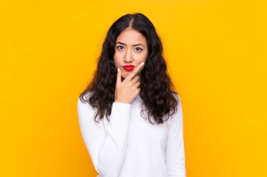 Karma ırk kadını, izole edilmiş sarı arka planda bir fikir düşünüyor.