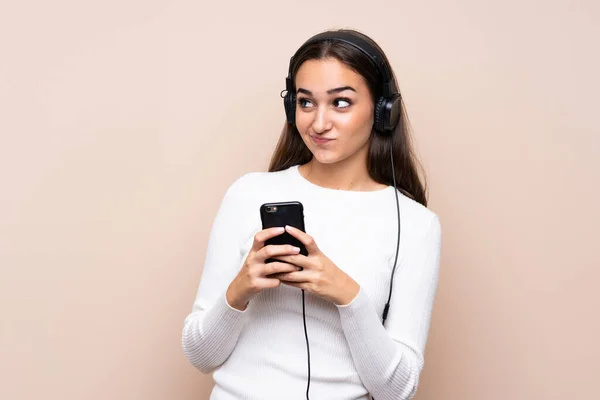 Mujer Joven Sobre Fondo Aislado Utilizando Móvil Con Auriculares Pensando — Foto de Stock