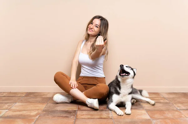 若いかわいい女性は 彼女のおずおずした犬が床の上に座って 屋内で手を携えて来るように誘います 来てくれて嬉しい — ストック写真