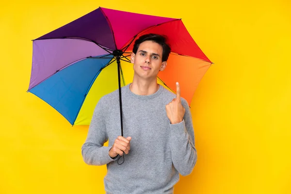Muž Drží Deštník Nad Izolovaným Žlutým Pozadím Ukazuje Ukazováčkem Skvělý — Stock fotografie