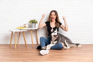 Genç ve güzel bir kadın, köpeğiyle yerde oturmuş zaferi kutluyor.