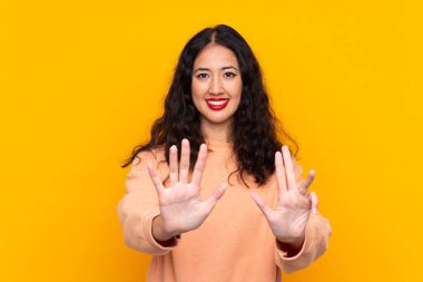 İspanyol Çinli kadın izole edilmiş sarı arka planda dokuz parmaklı sayıyor.