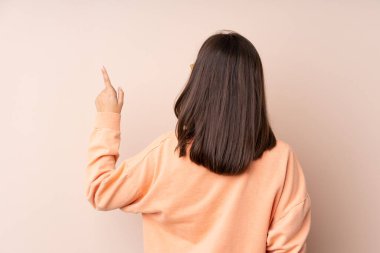İzole edilmiş arka planda genç bir kız işaret parmağıyla işaret ediyor.