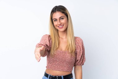 Genç Uruguaylı kadın izole edilmiş beyaz arka planda iyi bir anlaşma için el sıkışıyor.