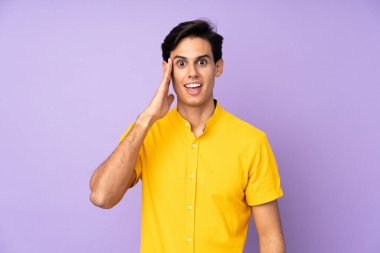 Şaşırmış ve şok olmuş yüz ifadesiyle izole edilmiş mor bir arka plan.