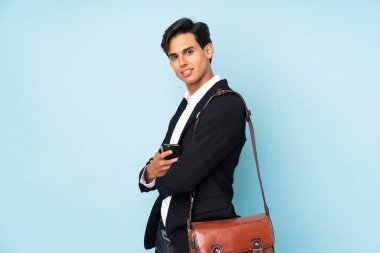 İzole edilmiş mavi arkaplan üzerinde iş adamı yana bakıyor