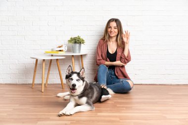 Köpeği evde yerde oturan genç kız parmaklarıyla 