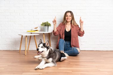 Köpeğiyle birlikte yerde oturan genç bir kız harika bir fikri işaret ediyor.