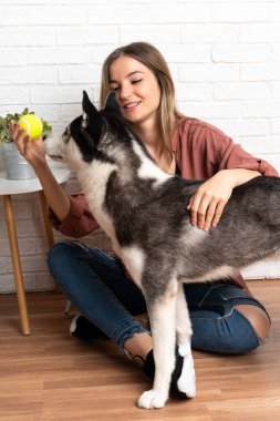 Genç ve güzel bir kadın. İri köpeğiyle içeride yerde oturuyor.