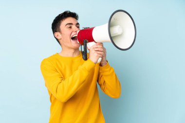 Mor arka planda izole edilmiş beyaz, yakışıklı genç bir adam megafondan bağırıyor.