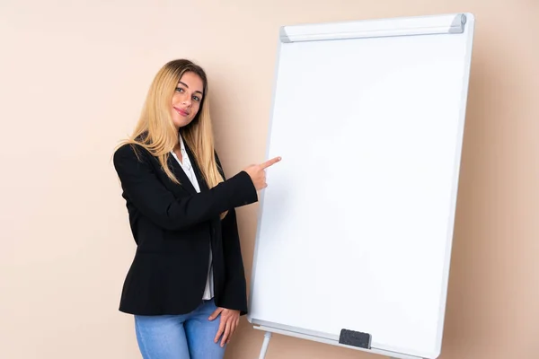 Young Uruguayan woman giving a presentation on white board and pointing to the side