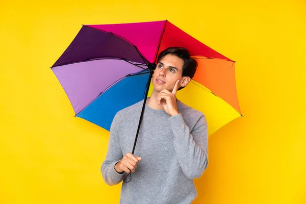 Hombre Sosteniendo Paraguas Sobre Fondo Amarillo Aislado Pensando Una Idea — Foto de Stock