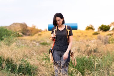 Genç dağcı kız dışarıda büyük bir sırt çantası taşıyor.