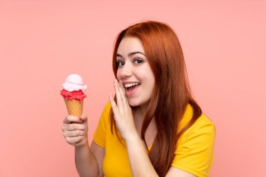Kornet dondurması olan genç bir kız izole bir arka planda bir şeyler fısıldıyor.