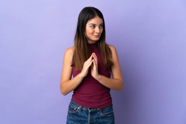 Mor arka planda izole edilmiş genç beyaz kadın bir şeyler planlıyor.