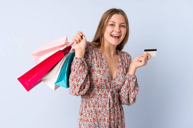 Genç Ukraynalı kız mavi arka planda izole edilmiş. Elinde alışveriş torbaları ve bir kredi kartı var.