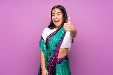 Genç Hintli kadın sari ile izole edilmiş, başparmakları yukarıda çünkü iyi bir şey oldu.