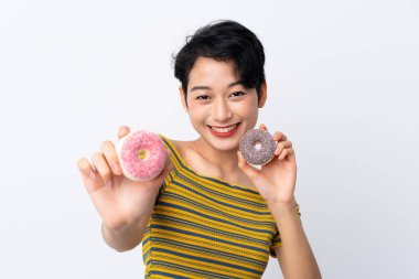 Genç Asyalı kız elinde mutlu bir ifadeyle donut tutuyor.