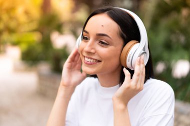 Açık havada müzik dinleyen genç bir kadın.