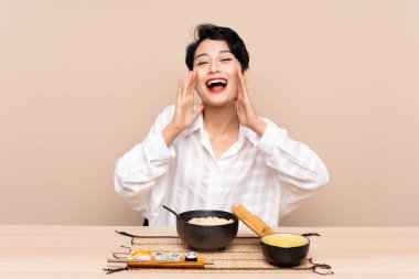 Genç Asyalı bir kız bir kase erişte ve sushi ile ağzı açık bağırıyor.