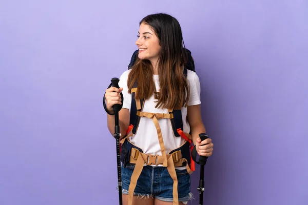 Jovem Com Mochila Postes Trekking Isolados Fundo Roxo Rindo Posição — Fotografia de Stock