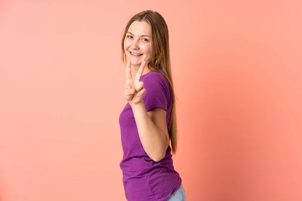 ティーンウクライナ人の女の子絶縁オンピンクの背景笑顔と示す勝利のサイン — ストック写真