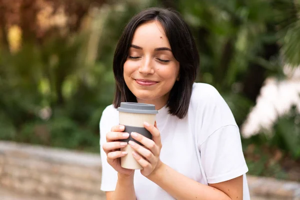 年轻漂亮的女人拿着咖啡到外面去喝 — 图库照片